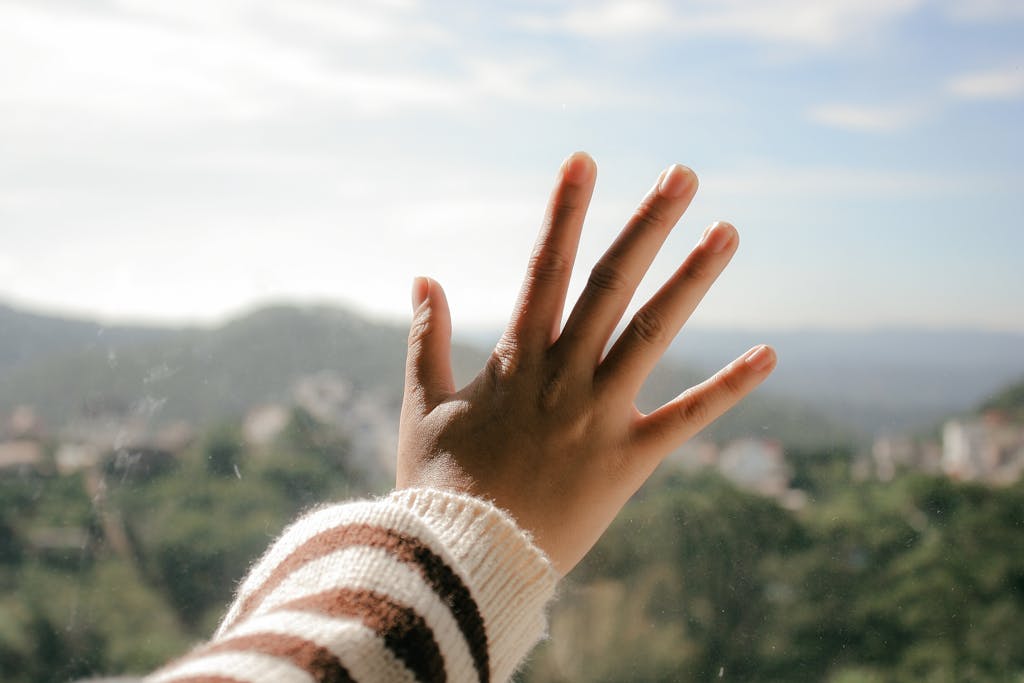 A hand touching glass with a stunning view of Đà Lạt, Vietnam in the background.