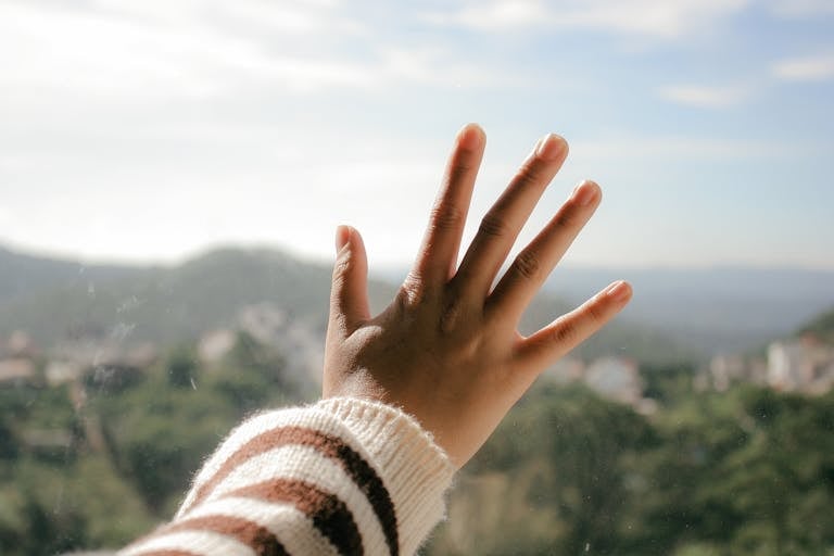A hand touching glass with a stunning view of Đà Lạt, Vietnam in the background.